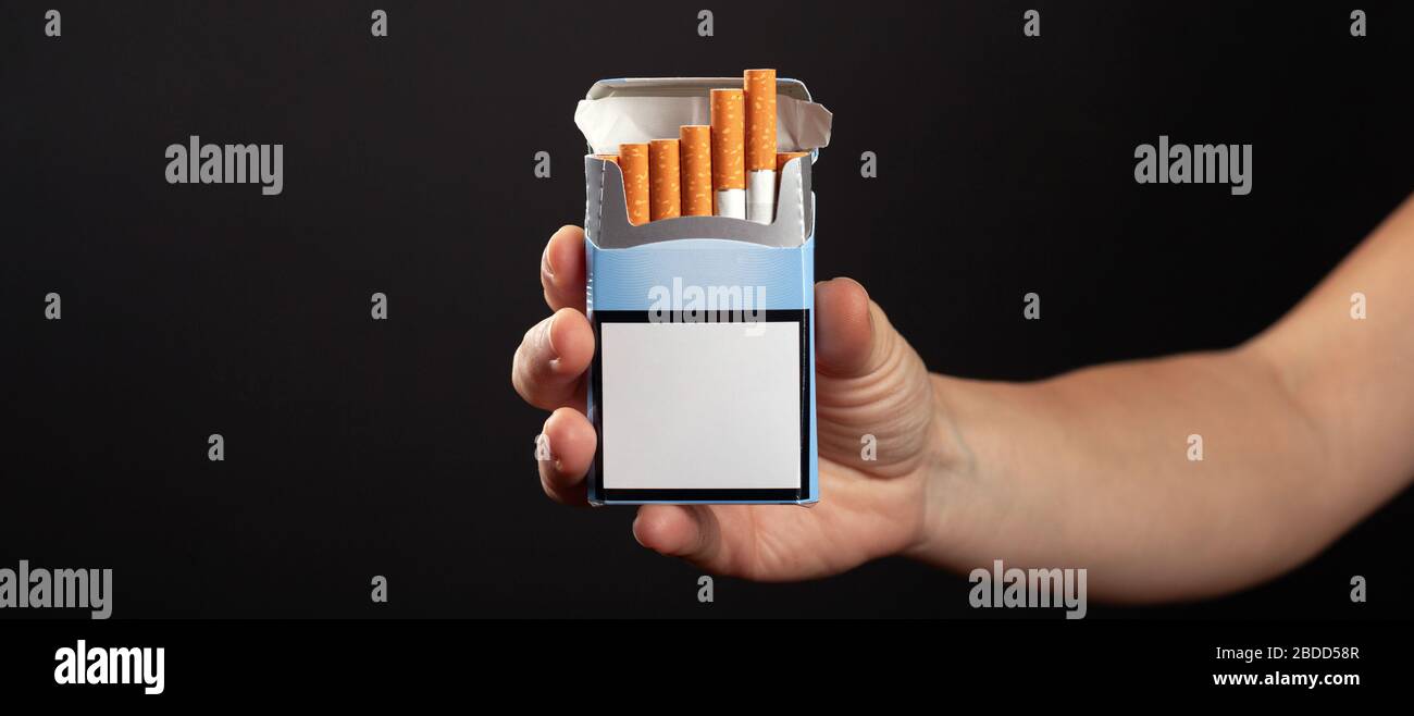 Zigarettenschachtel in der Hand auf dunklem Hintergrund. Zigarettenwerbung. Stockfoto