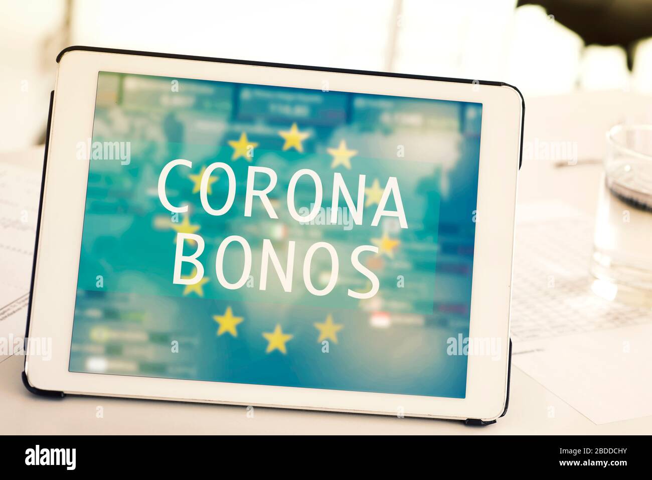 Nahaufnahme eines digitalen Tabletts, mit den in spanisch geschriebenen Textkorona-Anleihen auf dem Bildschirm, auf einem weißen Schreibtisch neben einigen gedruckten Tabellen Stockfoto