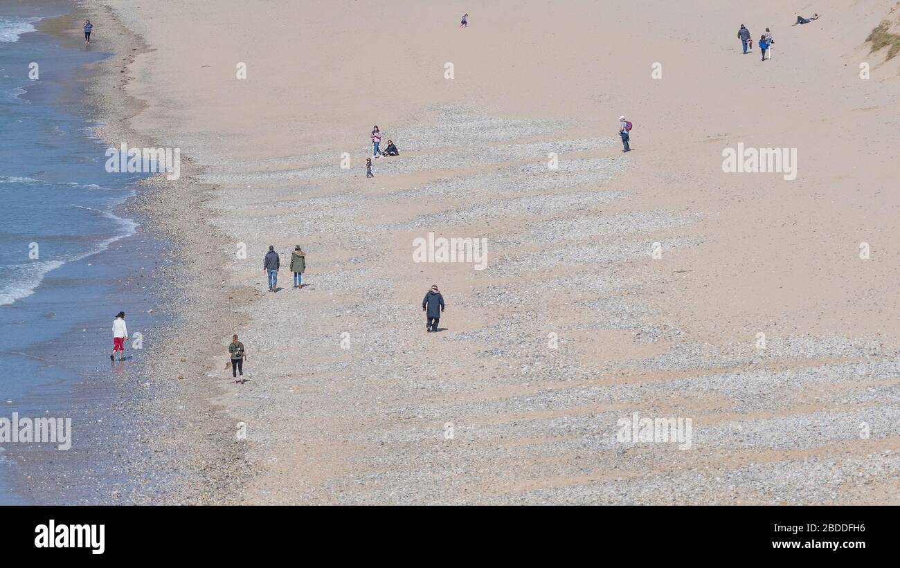 Ein Panoramablick auf Menschen, die am Fistral Beach in Cornwall spazieren gehen und aufgrund der Coronavirus Covid 19-Pandemie soziale Distanzierung aufrechterhalten. Stockfoto