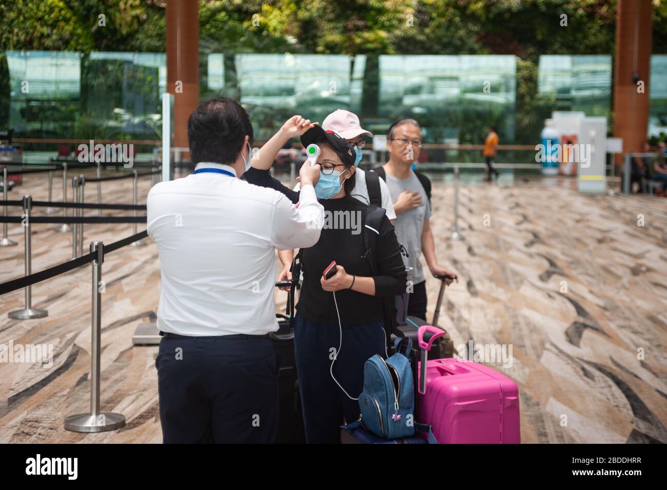 18.03.2020, Singapur, Singapur - ein Flughafenmitarbeiter wird die Körpertemperatur der Passagiere auf Fieber messen, bevor sie in Changi einchecken können Stockfoto