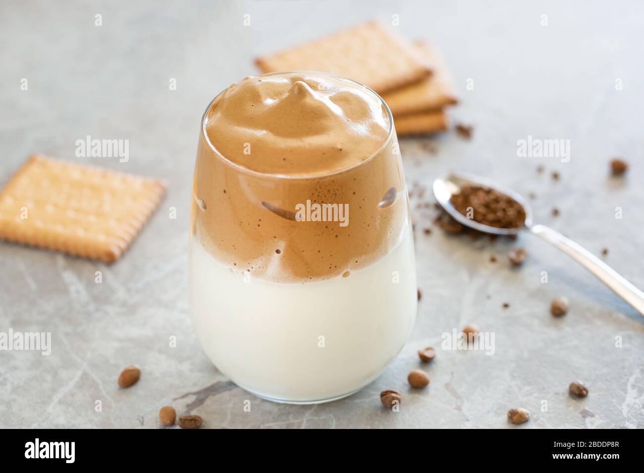 Dalgona Kaffee Creme mit Milch in Glasbecher mit Löffel im Hintergrund Stockfoto