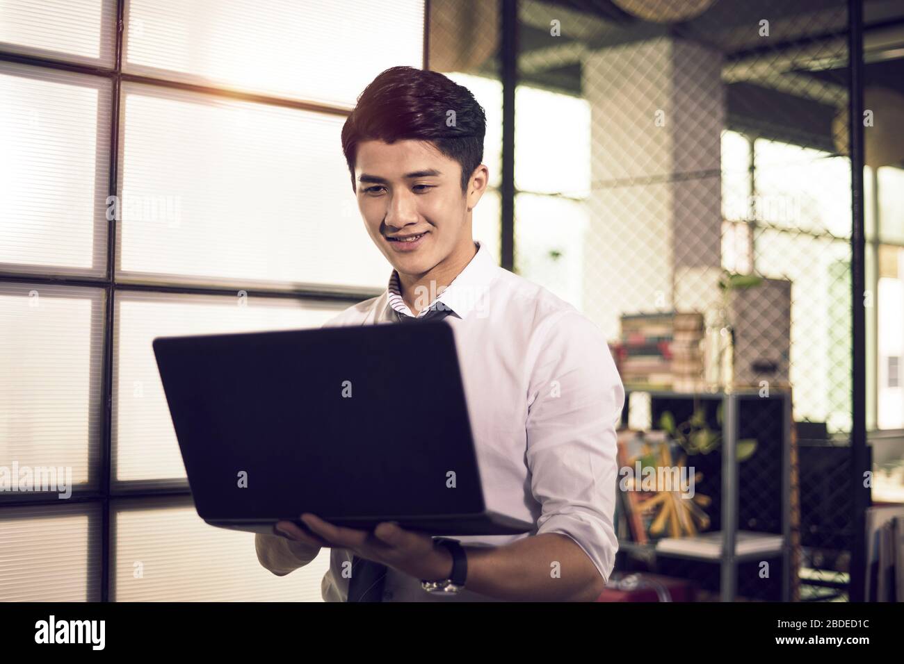 Junger unternehmer in asien, der Informationen oder Daten mit einem Laptop im Büro überprüft Stockfoto