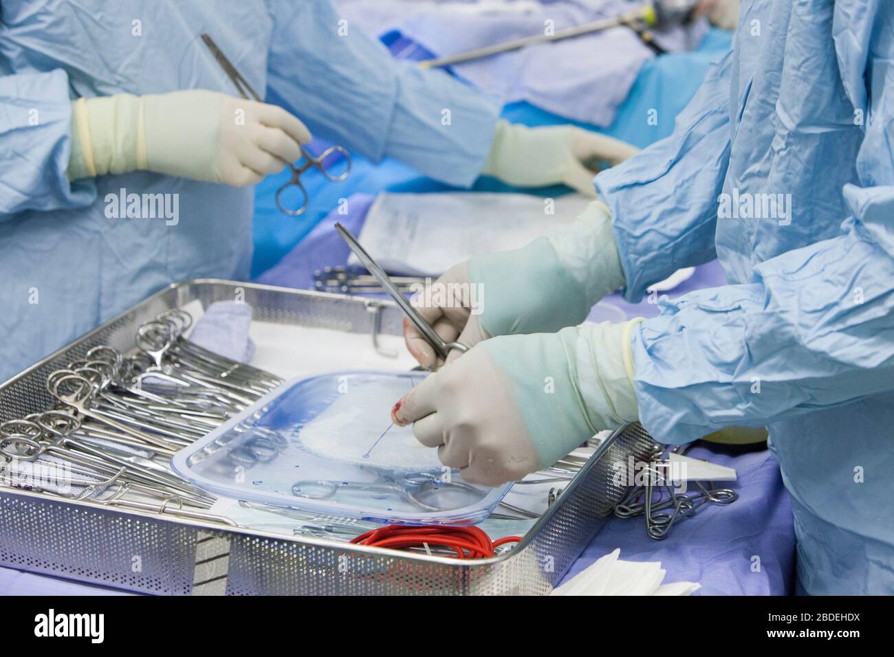 Chirurgen reicht während einer Operation in einem NHS-Krankenhaus eine Instrumentenschale ein. Der NHS steht mit der Coronavirus-Pandemie unter erhöhtem Druck. Stockfoto