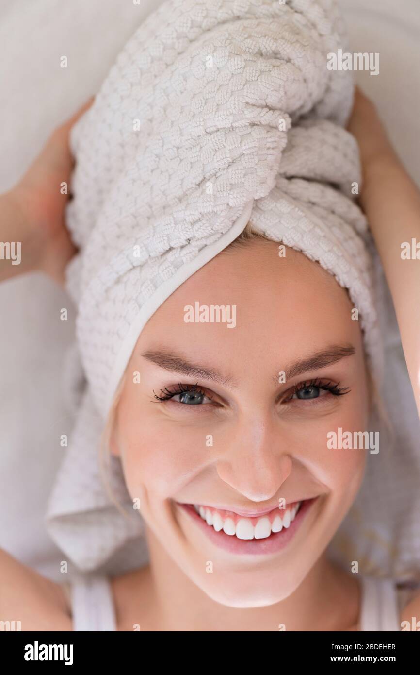 Porträt einer lächelnden Frau mit Kopf in Handtuch gewickelt Stockfoto