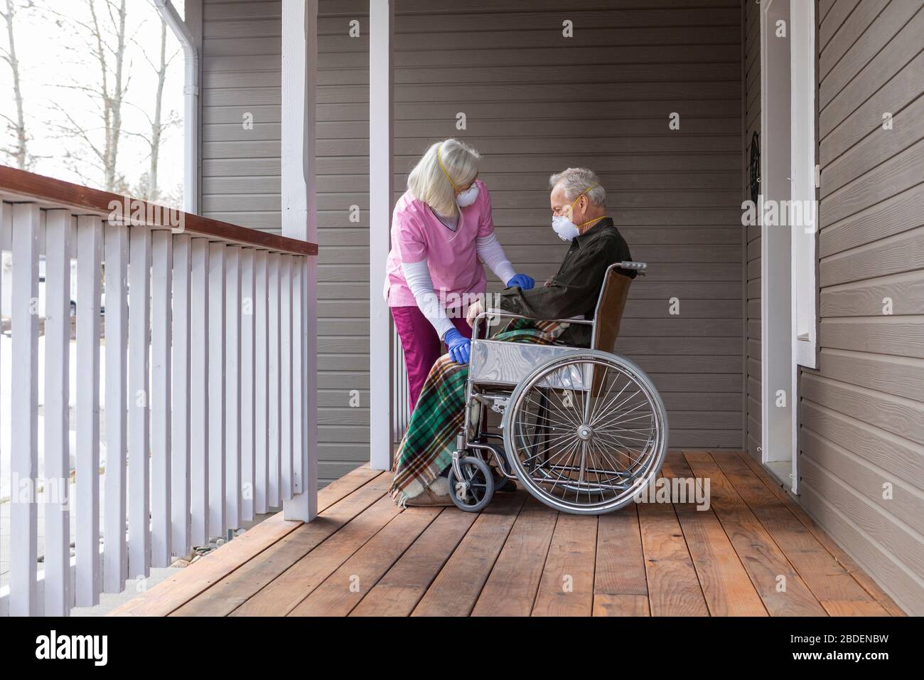 Frau und Mann im Rollstuhl tragen Schutzmaske zu verhindern Coronavirus-Übertragung auf der Veranda Stockfoto
