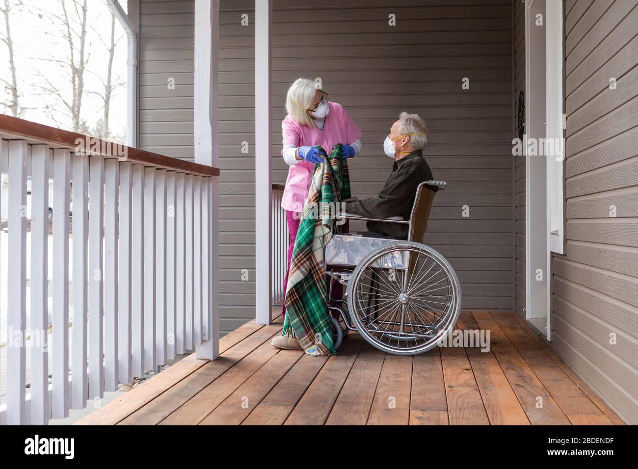 Frau und Mann im Rollstuhl tragen Schutzmaske zu verhindern Coronavirus-Übertragung auf der Veranda Stockfoto