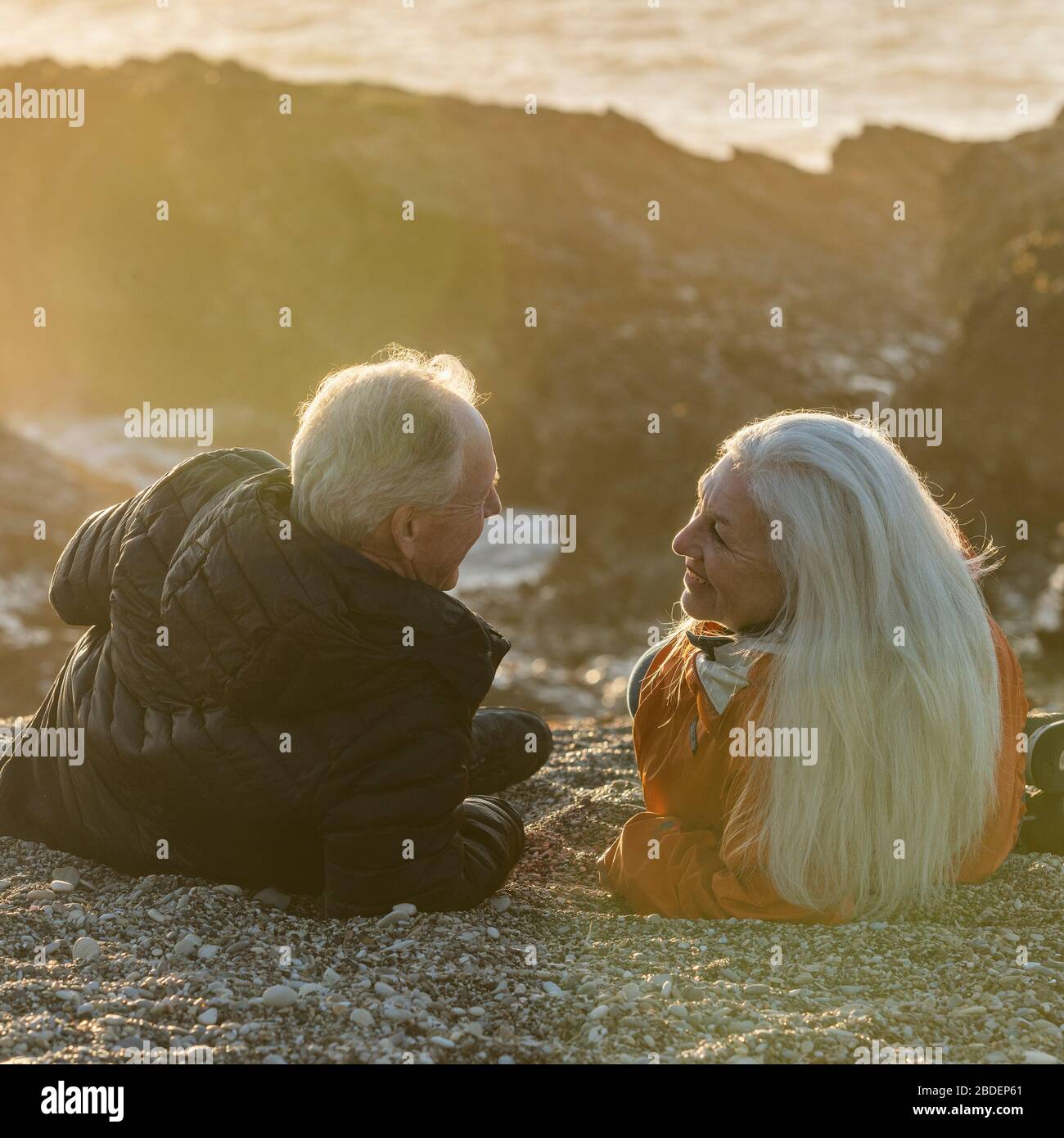 Ältere Paare genießen den Sonnenuntergang am Strand Stockfoto