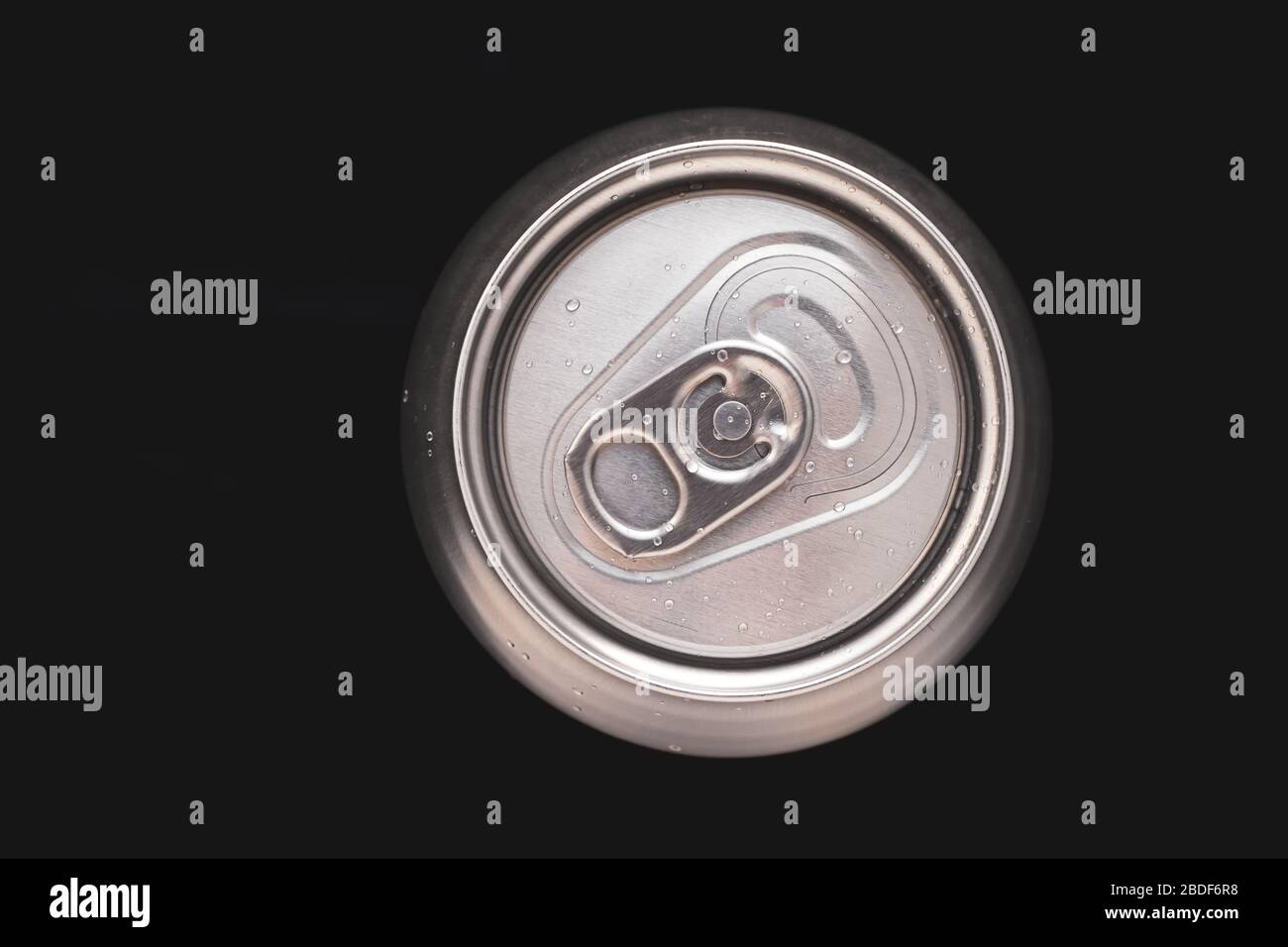 Metall-Soda-Dose mit Wassertropfen auf schwarzem Hintergrund. Draufsicht auf ein Bier aus Aluminium. Metallischer Getränkebehälter, Getränk. Runde Stahloberfläche Stockfoto
