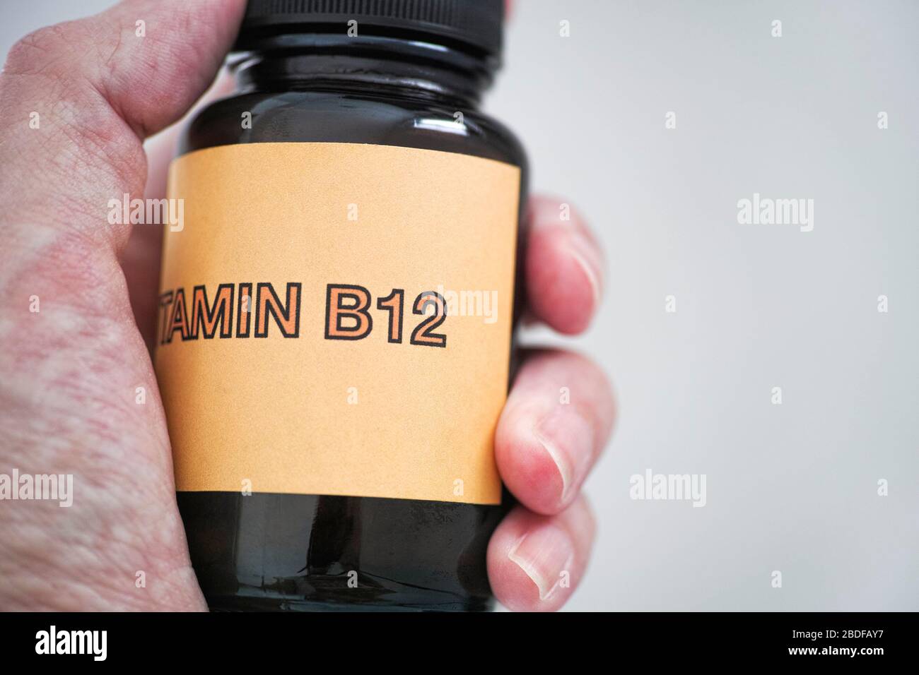Person, die eine Flasche Vitamin B12 hält. Nahaufnahme. Stockfoto