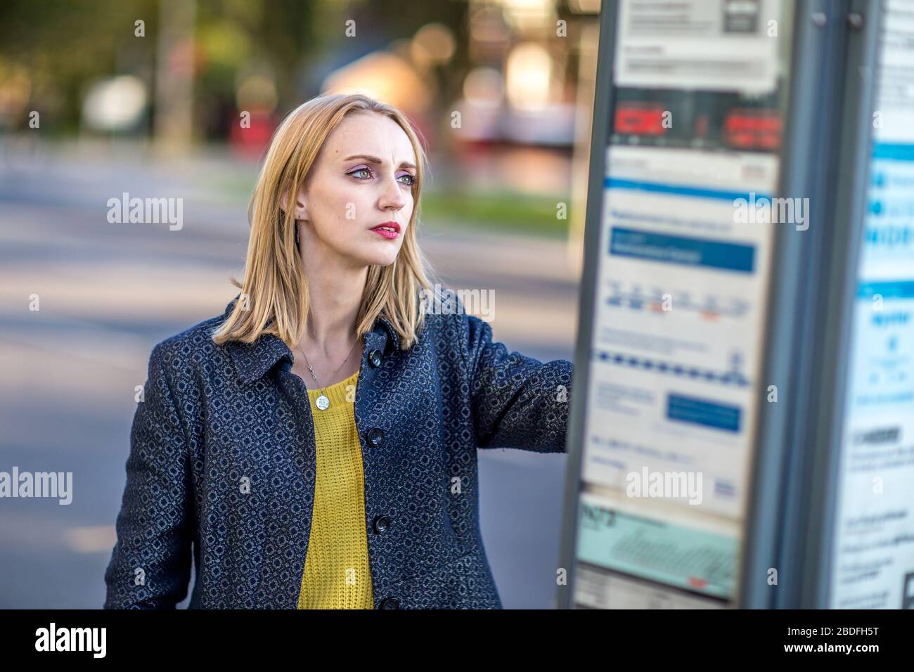 Junge Frau schaut auf den Busfahrplan Stockfoto