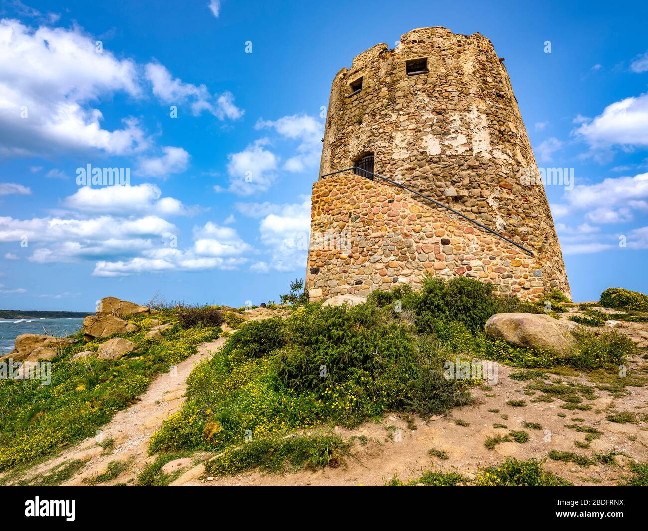 Nahaufnahme von 'Torre di Barì', einem Turm auf einem Felsvorsprung am Strand mit beigem Sand und Meer mit kristallklarem Wasser, Bari Sardo, Sardinien, Italien Stockfoto