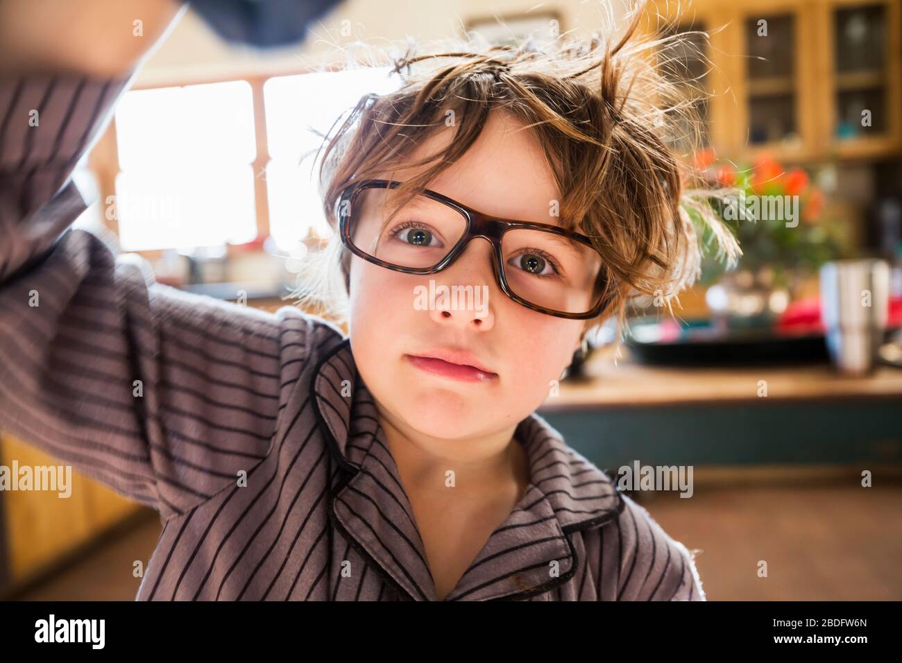 Porträt eines sechsjährigen Jungen mit geschälten Haaren und übergroßen Brillen, die aufwachen. Bettkopfhaar. Stockfoto