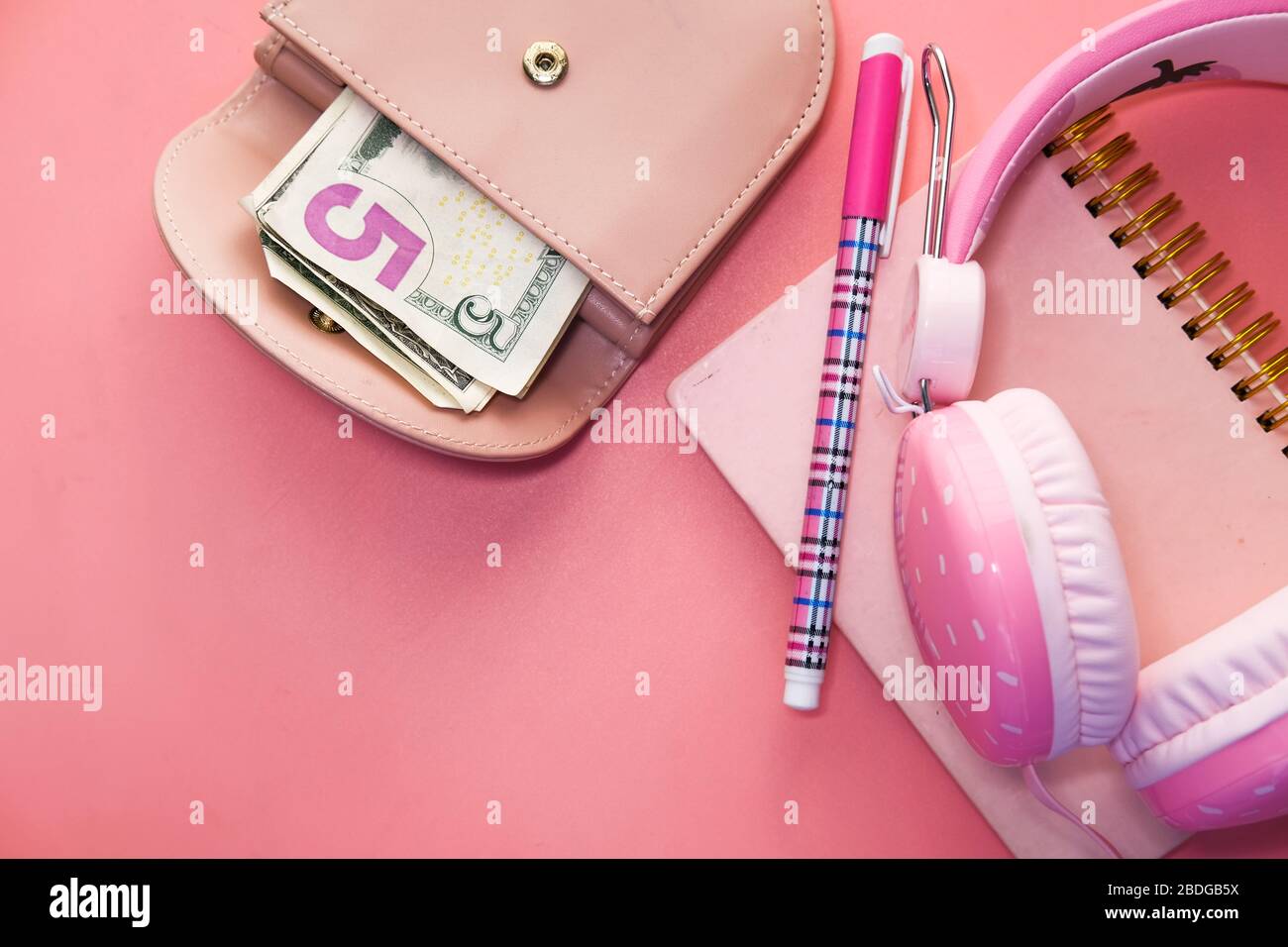 Tisch mit Notizblock, Kopfhörer, Bargeld und Stift. Stockfoto