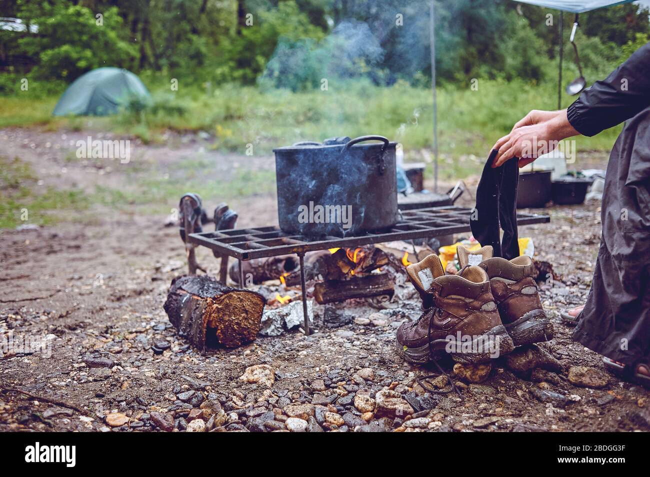 Nasse Touristen wandern um das Lagerfeuer und trocknen ihre Kleidung. Im Wald durchnässt Stockfoto