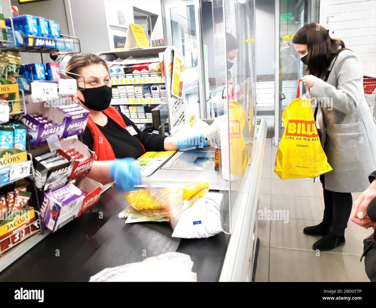 Ukraine, Kiew am 7,2020. März.Woman Kassierer in einer schwarzen medizinischen Maske akzeptiert die Zahlung für die Waren von einem Mädchen in Billa Shop während der Quarantäne der Stockfoto