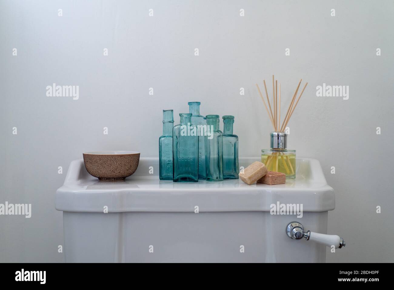 Eine Sammlung von unruhigen Gegenständen, die auf einer sauberen weißen toiletten-zisterne angezeigt werden Stockfoto