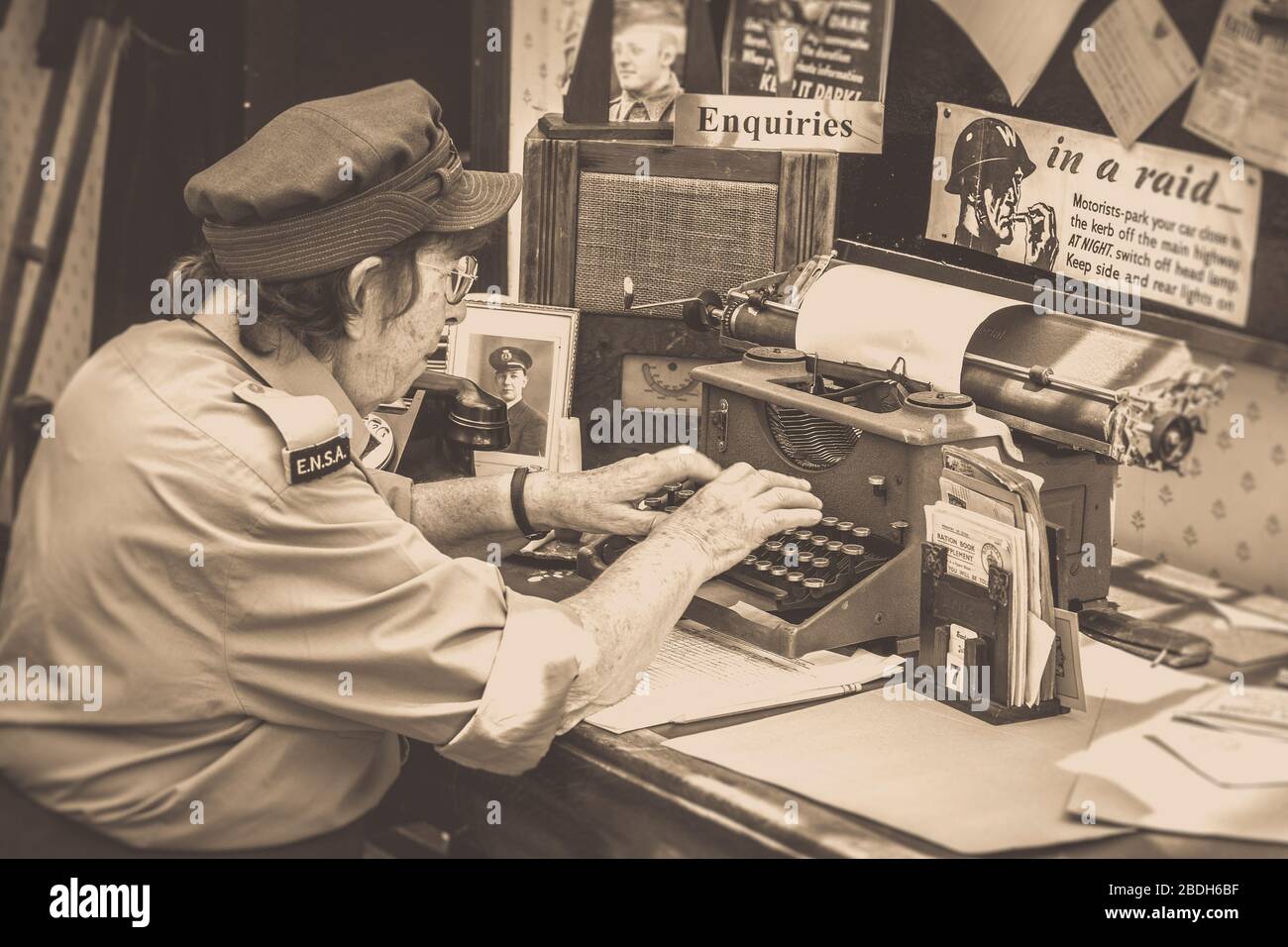 Ältere Frau in Uniform arbeitet isoliert in Vintage-Büro auf altmodische Schreibmaschine bei 1940er WWII Kriegszeit Ereignis, Großbritannien. Berufstätige Frauen. Stockfoto