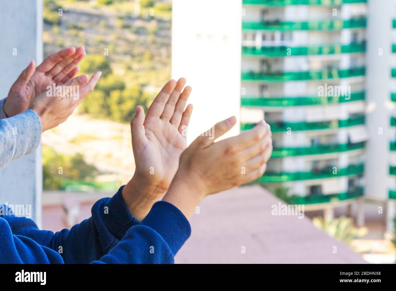 Die Familie lobt das medizinische Personal vom Balkon. Menschen klatschen auf Balkons und Fenstern, um die Gesundheit der Mitarbeiter während der Coronavirus Pandemie zu unterstützen Stockfoto