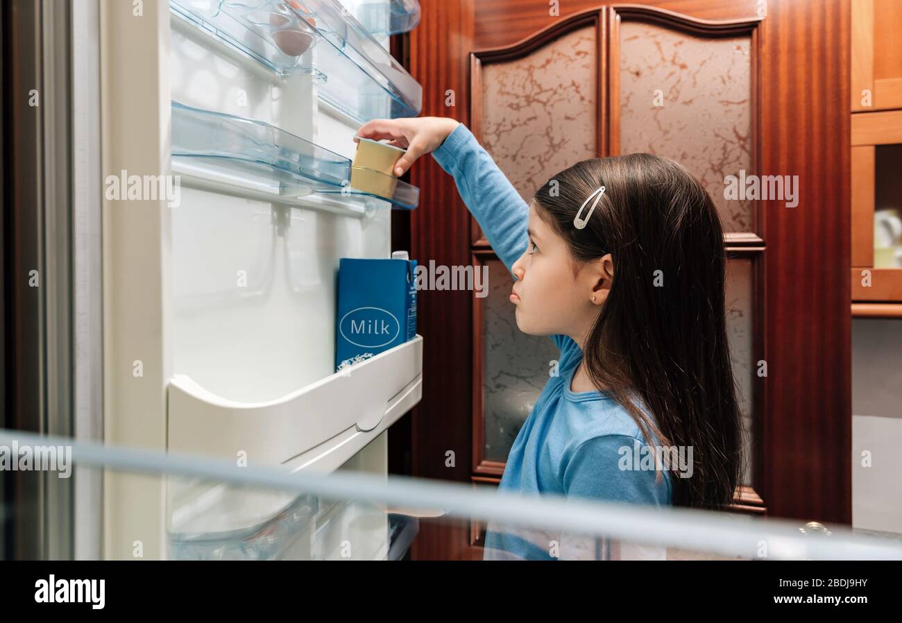 Trauriges Mädchen, das den letzten Joghurt aus dem Kühlschrank nimmt Stockfoto