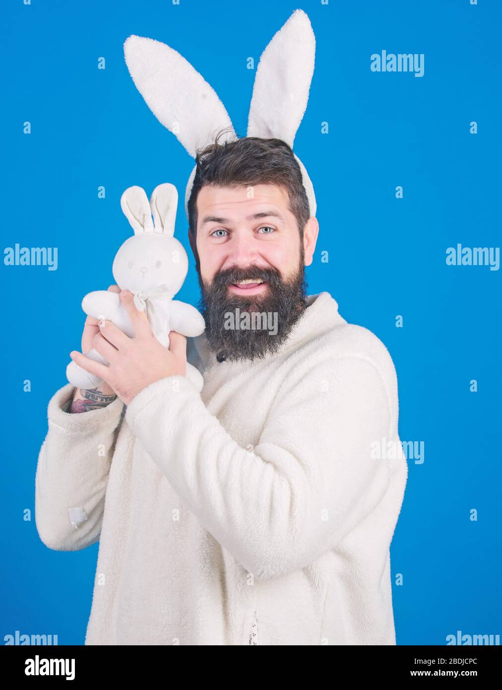 Osterhase. Respekt vor Traditionen. Mann trägt einen kuscheligen Plüschanzug. Lustiger Hünenmann mit Bart und Schnurrbart. Konzept des Ostersymbols. Kerl bärtiger Flusspferd süßer sanfter, bunter langer Ohren blauer Hintergrund. Stockfoto