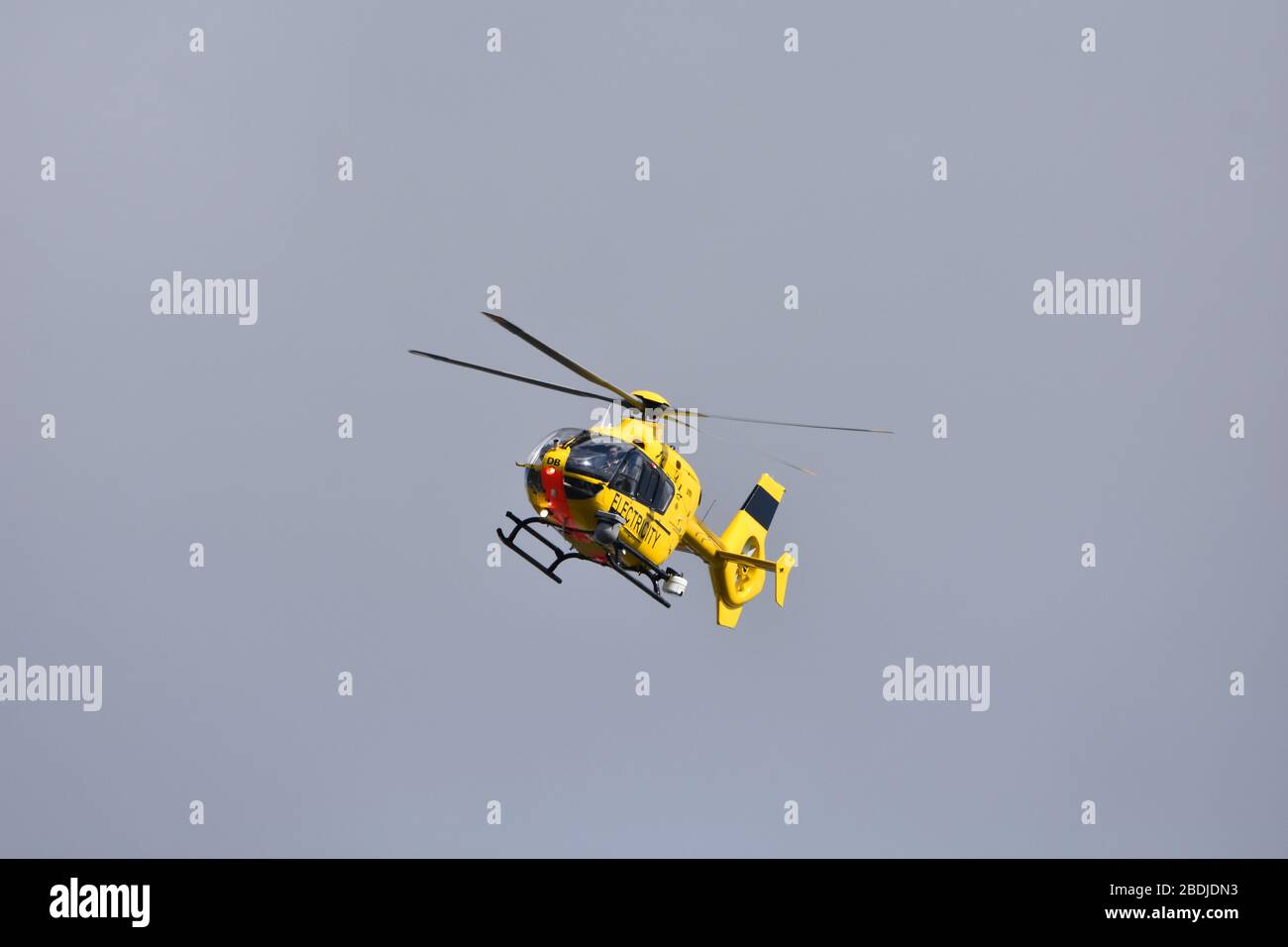 Der gelbe Elektrohubschrauber WPD EC 135 am Himmel über dem Bristol International Airport, England, Großbritannien. Durchführung der Wartung der Elektrizität Stockfoto