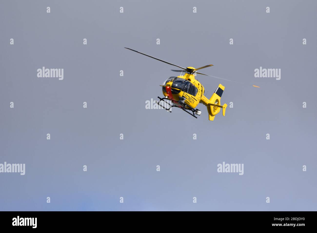 Der gelbe Elektrohubschrauber WPD EC 135 am Himmel über dem Bristol International Airport, England, Großbritannien. Durchführung der Wartung der Elektrizität Stockfoto