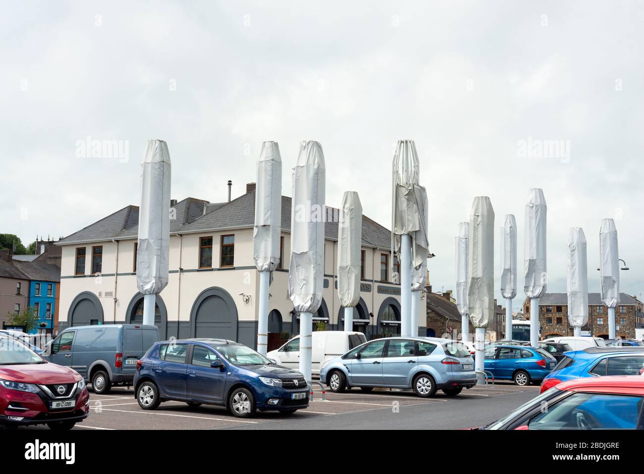 Geparkte Autos auf dem Parkplatz Quays oder Nealon's Quayside Parkplatz mit großen zusammengeklappten Tulip Architekturschirmen in Youghal, Irland, seit 2018 Stockfoto