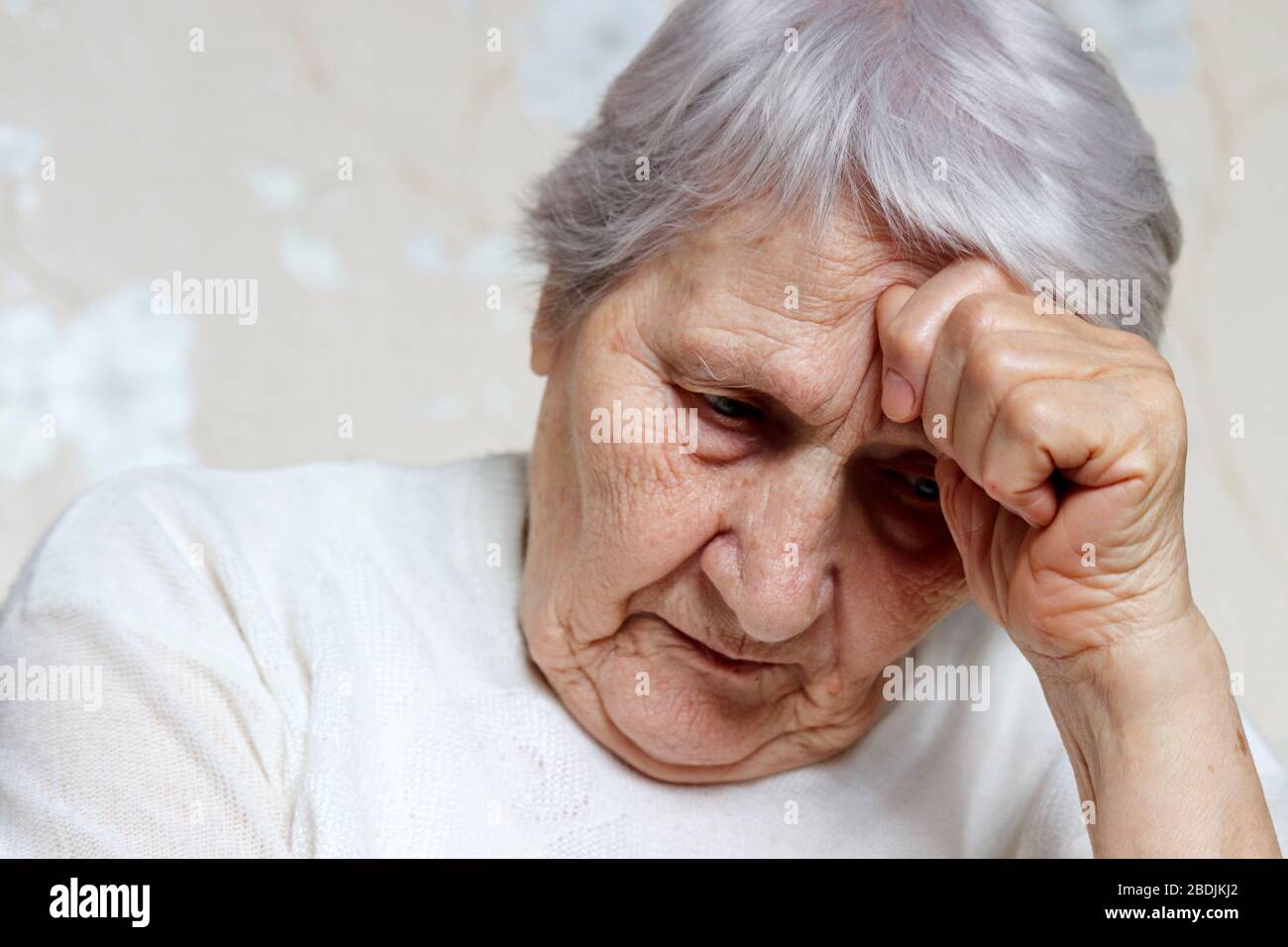 Ältere Frau dachte über etwas nach. Trauriges Weibchen mit grauem Haar und zerknitterter Haut, Konzept von Kopfschmerzen, Erinnerungen, Einsamkeit und Alter Stockfoto