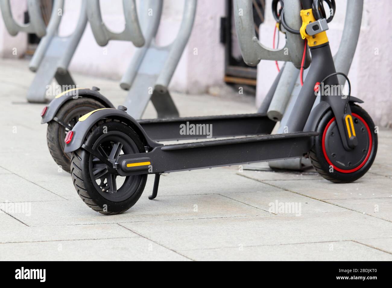 Elektrische Roller hintereinander auf dem Parkplatz. Stadtradverleih, öffentliche E-Roller auf der Straße Stockfoto