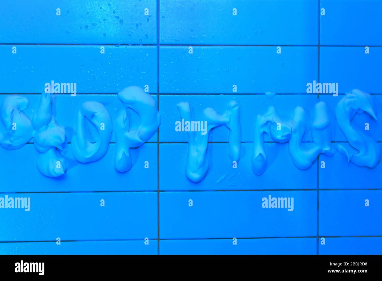 Die Beschriftung Schaum an der gefliesten Wand des Stoppvirus, mit ultravioletter Beleuchtung. Stockfoto