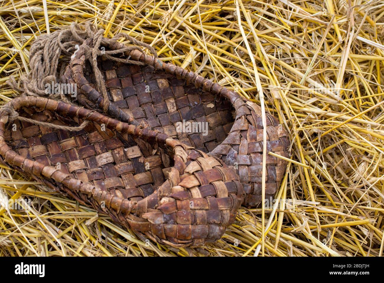 Bast Schuhe auf dem Stroh, traditionelle Weidenschuhe des alten Russland. Nahaufnahme Stockfoto