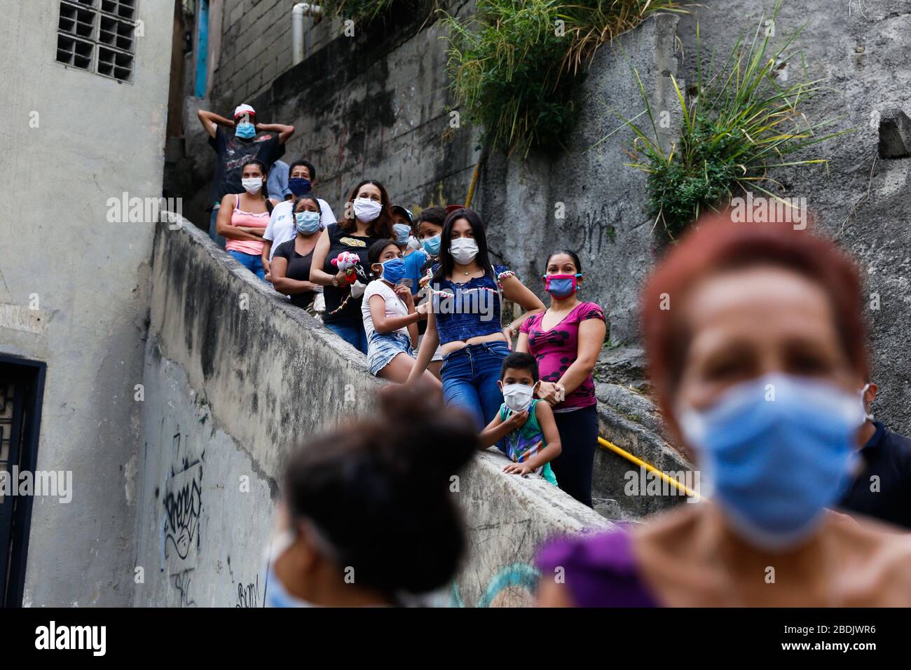 Caracas, Venezuela. April 2020. Jugendliche und Kinder mit Gesichtsmasken, die bei der Feier der Karwoche auf die Jesusfigur "Nazareno de San Pablo" warten. Die jährliche Prozession, bei der traditionell Pilger gemeinsam durch die Stadt gehen, findet dieses Jahr wegen der Ausreisebeschränkungen gegen die Ausbreitung des Coronavirus nicht statt. Die katholische Kirche hat beschlossen, die religiöse Figur durch die Hauptstadt zu treiben, damit die Gläubigen sie von zu Hause aus sehen können. Kredit: Rafael Hernandez / dpa / Alamy Live News Stockfoto