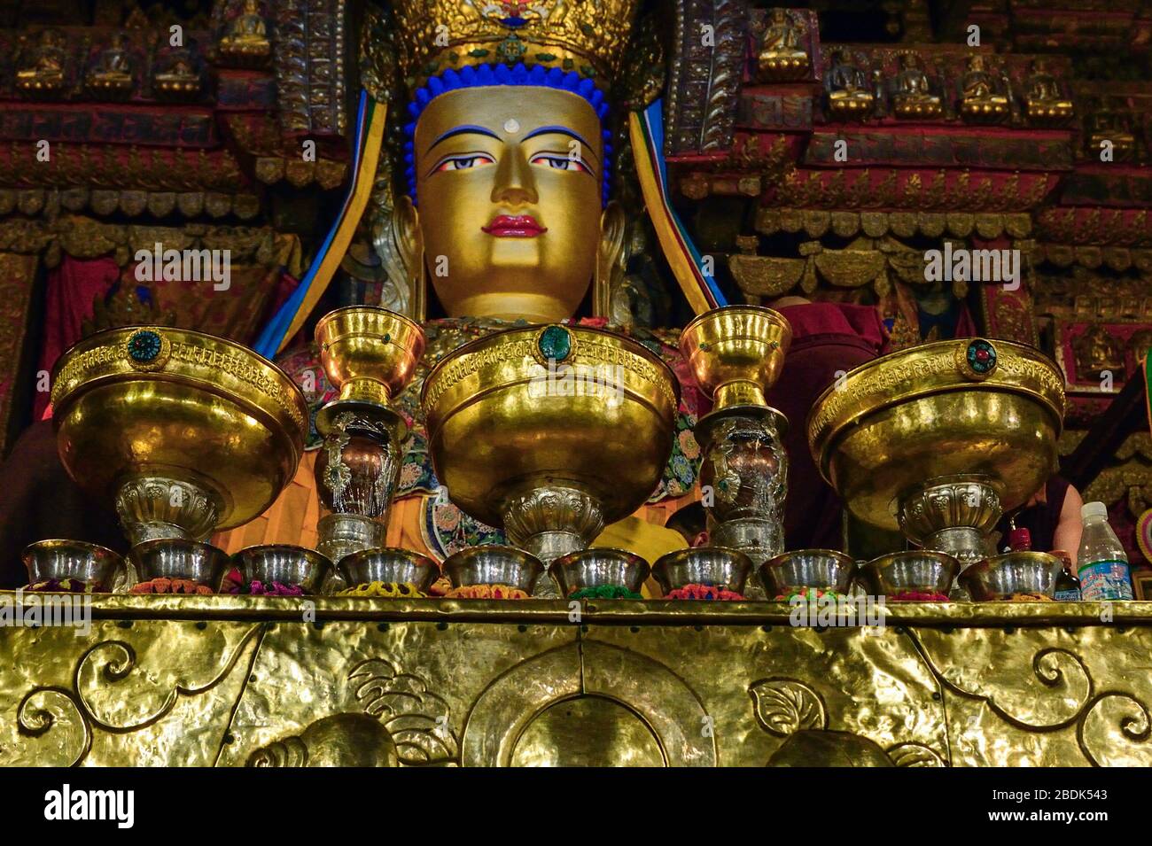 Ein alter vor einem goldenen Buddha ist sorgfältig mit verzierten Schalen und Kelchen für Opfergaben im Kloster Pelkor Chode in Gyantsein, dem Autonomen, verziert Stockfoto