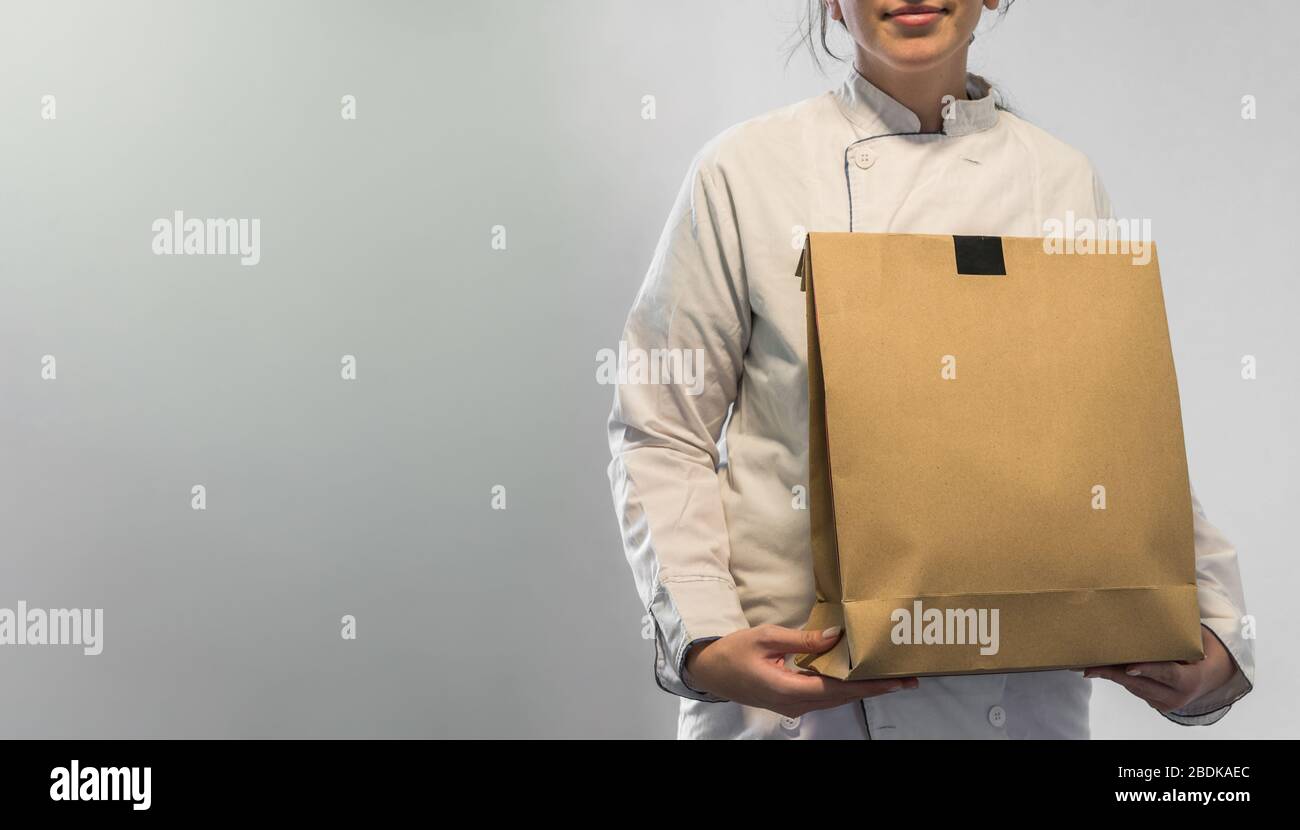Der Küchenchef nimmt Speisen in einer Papierkartontasche mit Platz für Kopien mit. Stockfoto
