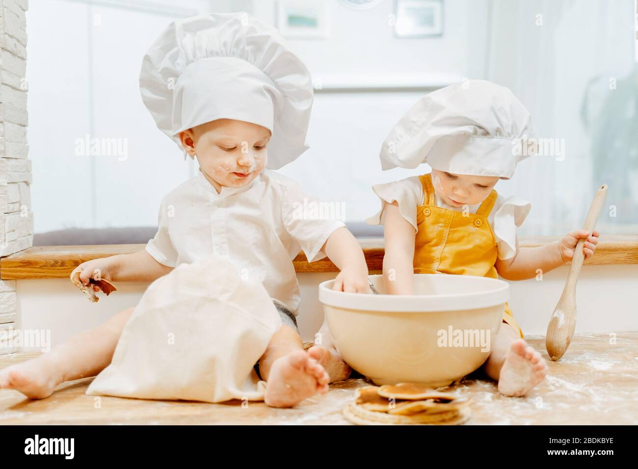 Charmante zweijährige Zwillinge Bruder und Schwester in weißer Kappe Stockfoto