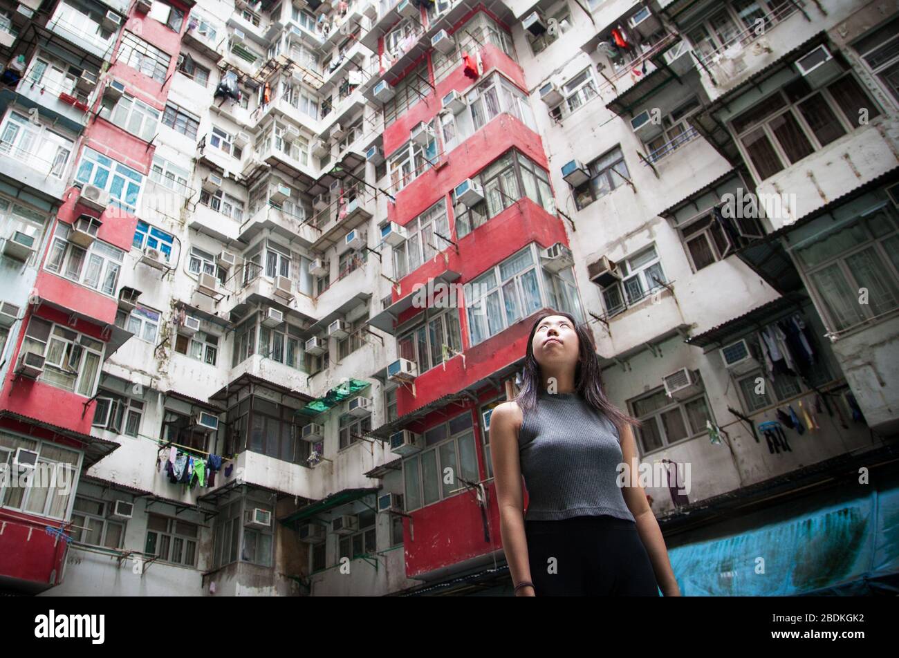 Chinesisches Mädchen, das auf die urbane Landschaft von Hongkongs zugestopften öffentlichen Wohnquartieren in Quarry Bay auf Hong Kong Island blickt. Stockfoto