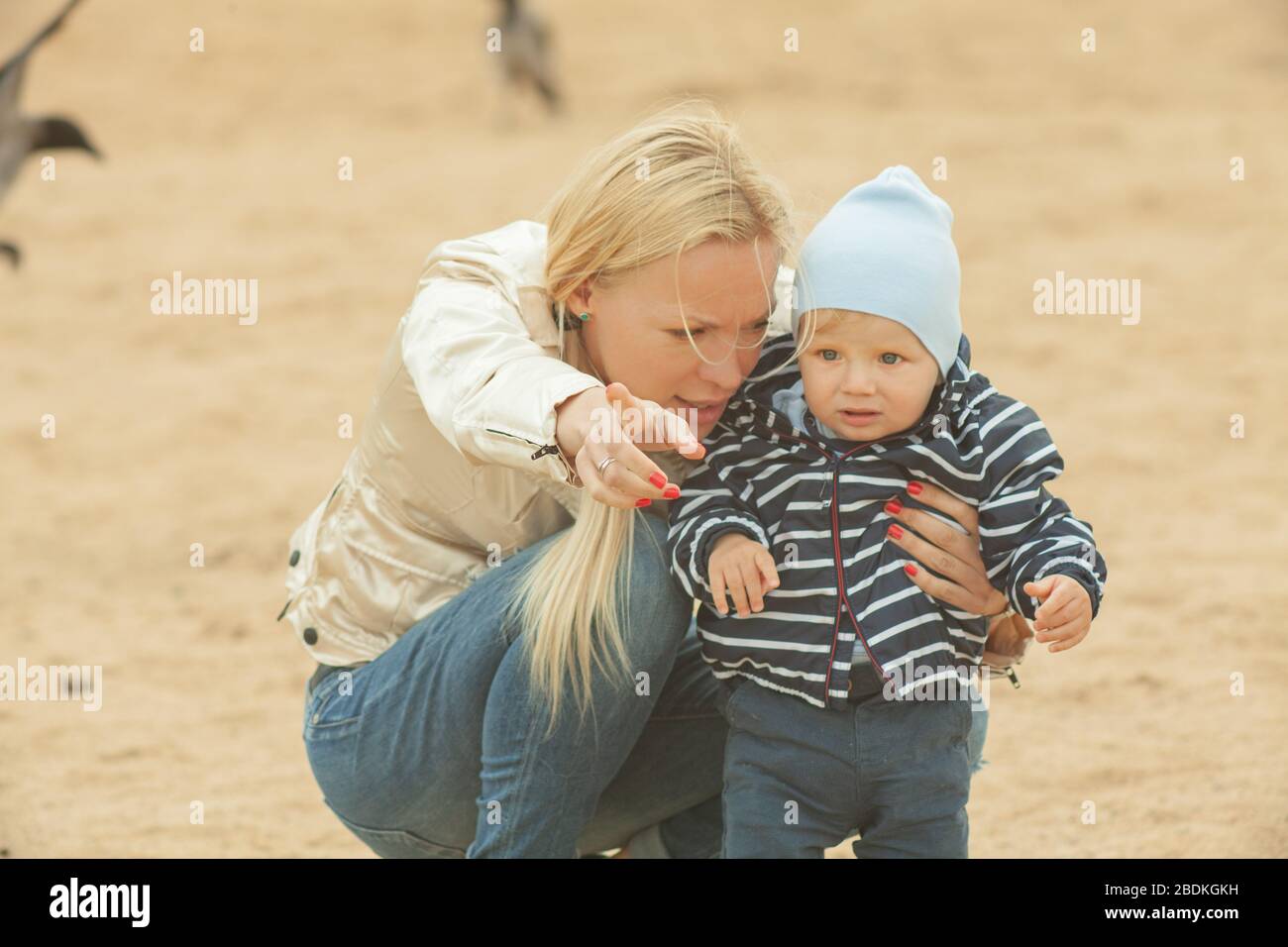 Eine Mutter mit langen Haaren hält ihren kleinen Sohn sanft in den Armen. Foto im Park mit Tageslicht Stockfoto