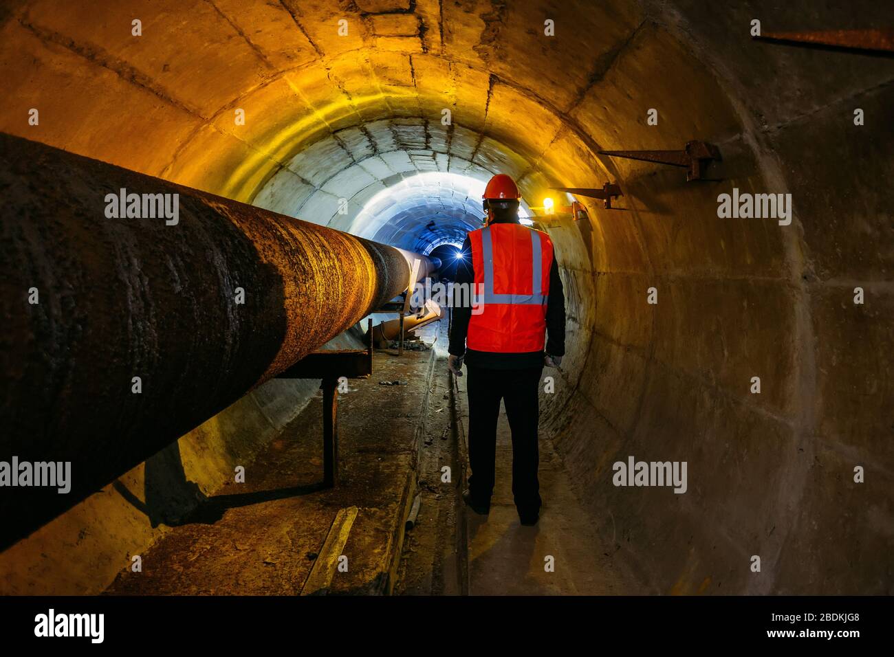 Tunnelarbeiter untersuchen Pipeline im unterirdischen Tunnel Stockfoto