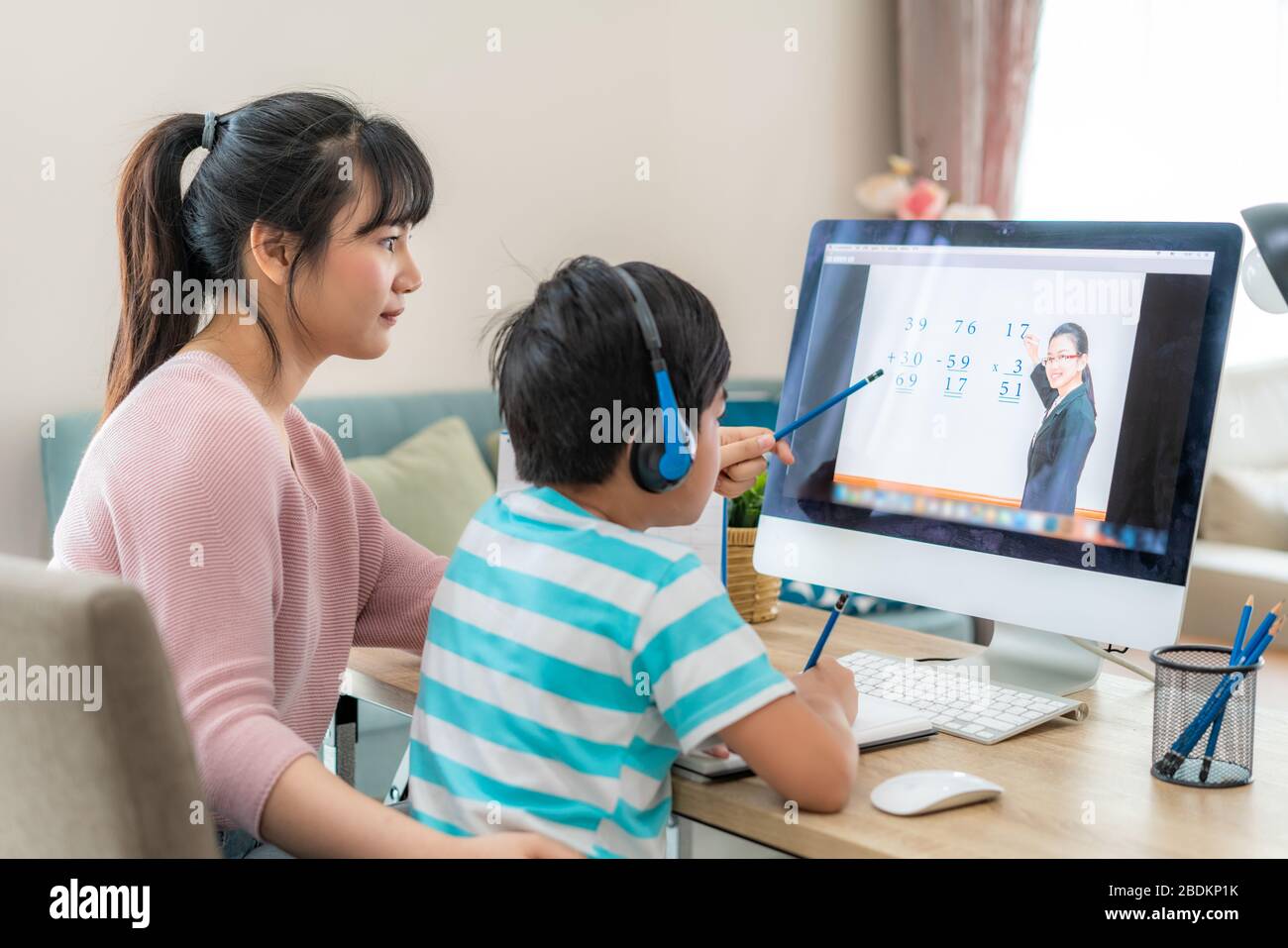 Asian Boy Student mit Mutter Videokonferenz E-Learning mit Lehrer am Computer im Wohnzimmer zu Hause. Homeschooling und Fernunterricht, online Stockfoto