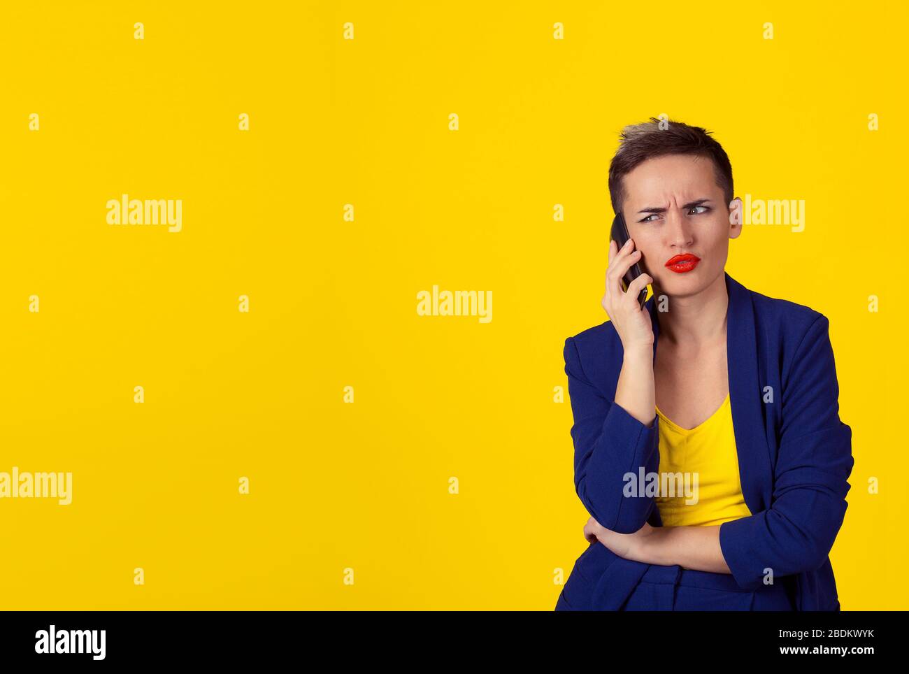 Skeptische Geschäftsfrau im Unglauben, auf dem Telefon zu sprechen, die entscheiden soll, was sie auf den Kopierbereich antworten soll, isolierte gelbe Hintergrundwand. Negativer Mensch e Stockfoto