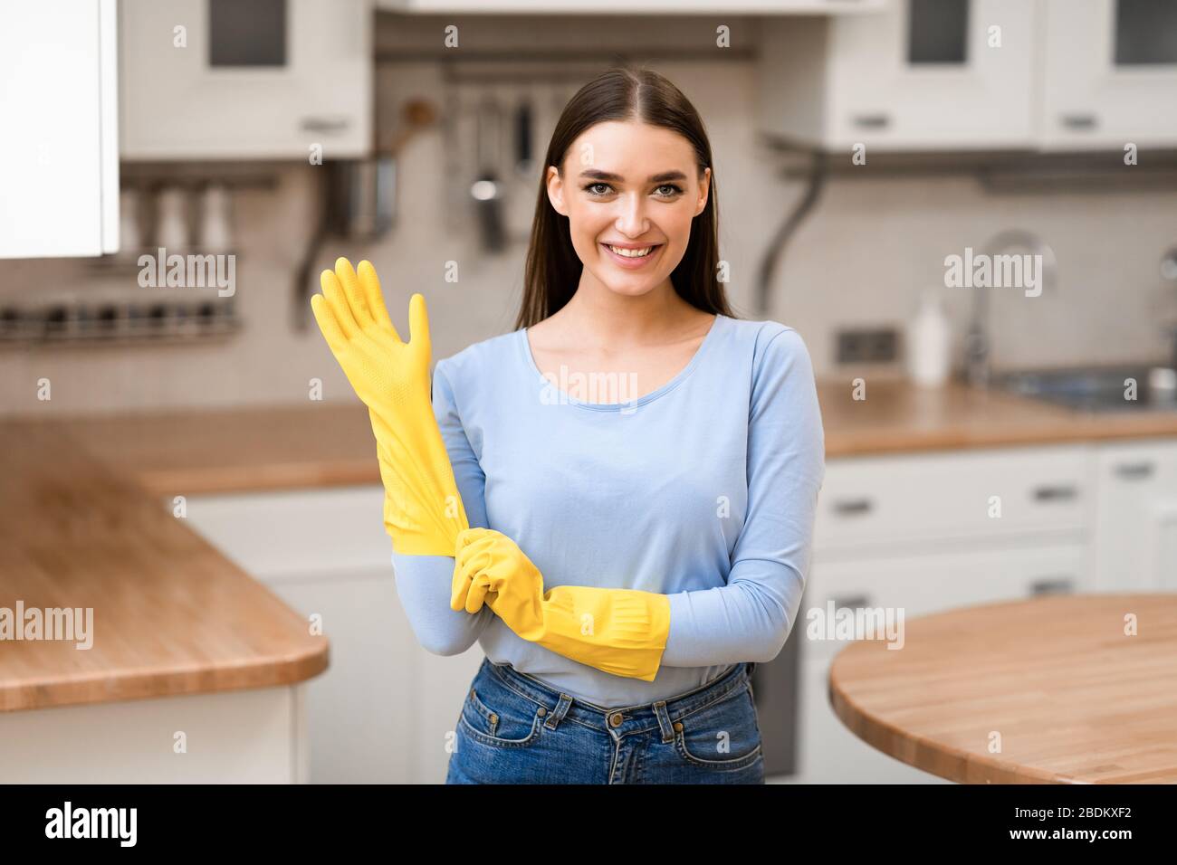Junge Frau, die gelbe Gummihandschuhe zur Hand hat Stockfoto
