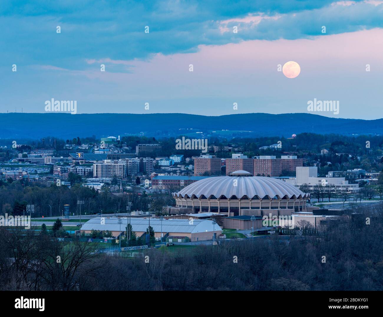 Morgantown, WV - 7. April 2020: Der superrosafarbene Mond erhebt sich über der coliseum-arena auf dem Evansdale Campus der WVU-Universität Stockfoto