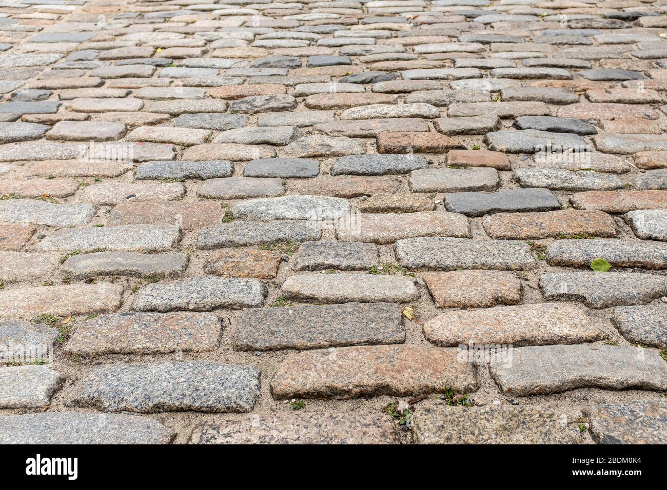 Eine alte Kopfsteinpflasterstraße an der Lower East Side von Manhattan. Reihen von Pflastern bilden ein unebenes Muster. Schöner Hintergrund oder Tapete. Stockfoto