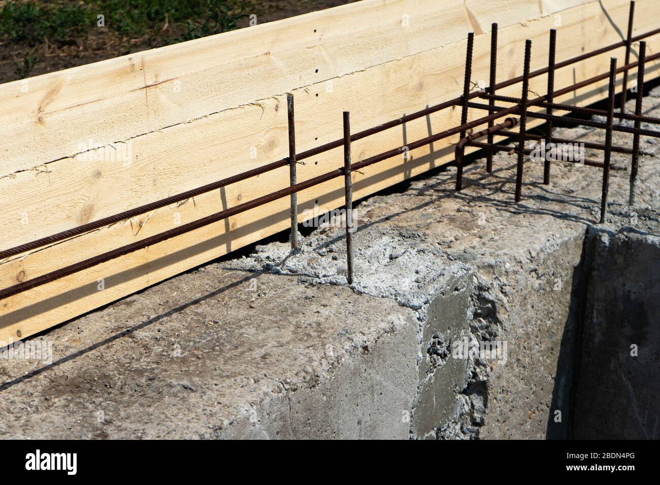 Schalung für die Grundierung des Hauses. Nahaufnahme des Hausfundaments aus Betonschalenblöcken mit Mörtel und Verstärkungsleisten gefüllt. Stockfoto