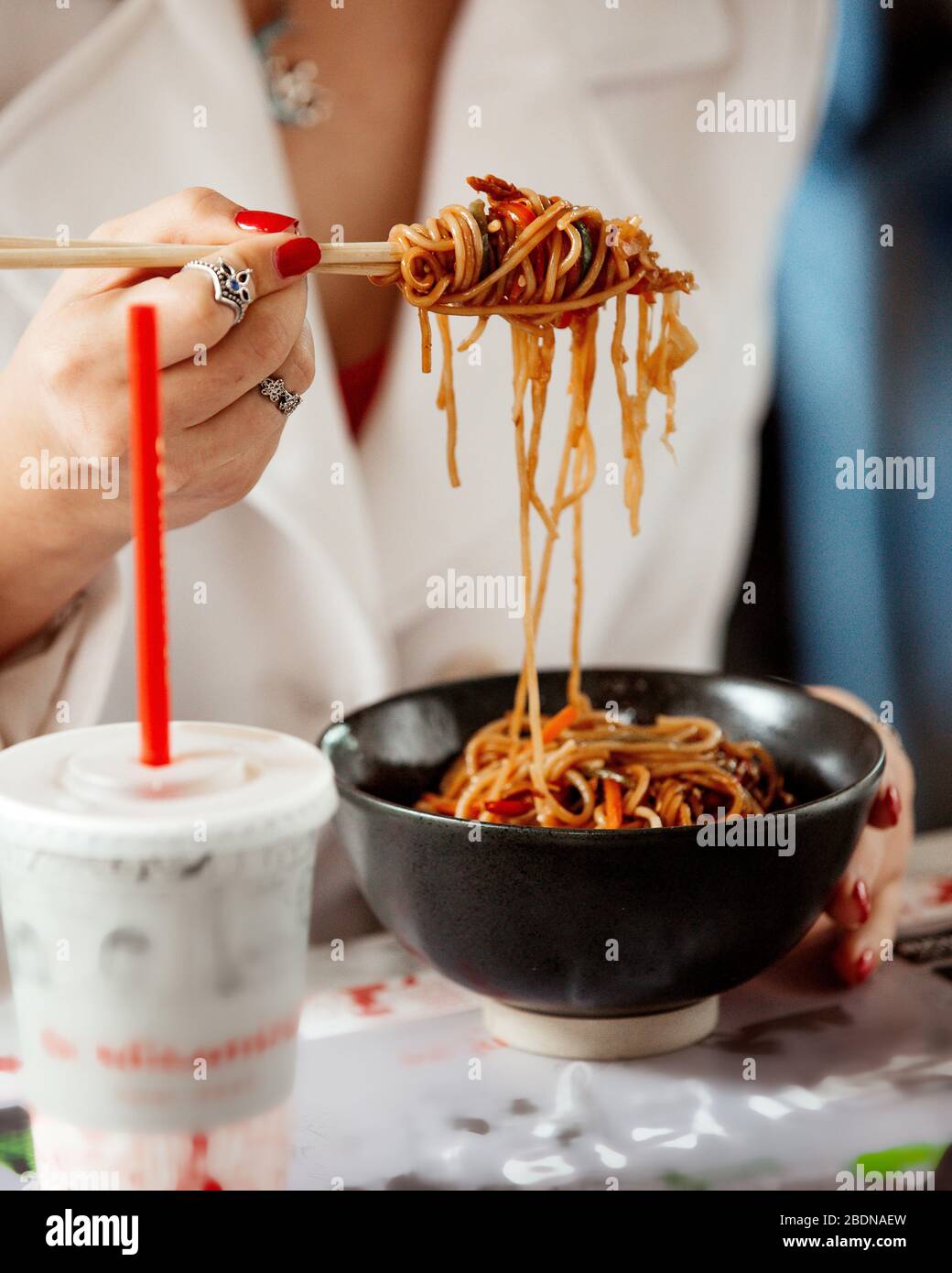 Mädchen hält Hühnernudeln auf Sushi-Sticks Stockfoto