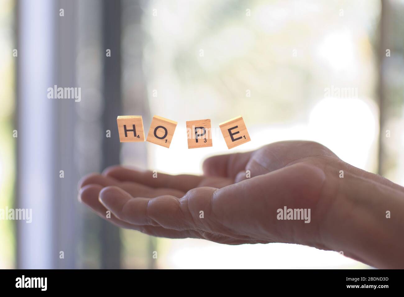 Scrabble Stücke bilden das Wort Hoffnung über die Hände - selektiver Fokus. Stockfoto