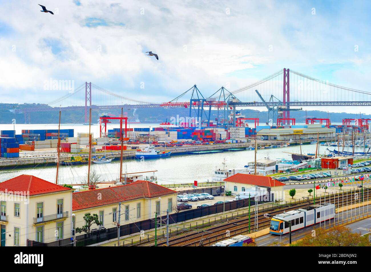 Möwen über dem Handelshafen von Lissabon, Schiffscontainer und Frachtkräne, Skyline mit Brücke vom 25. April und Fluss Tejo, Portugal Stockfoto