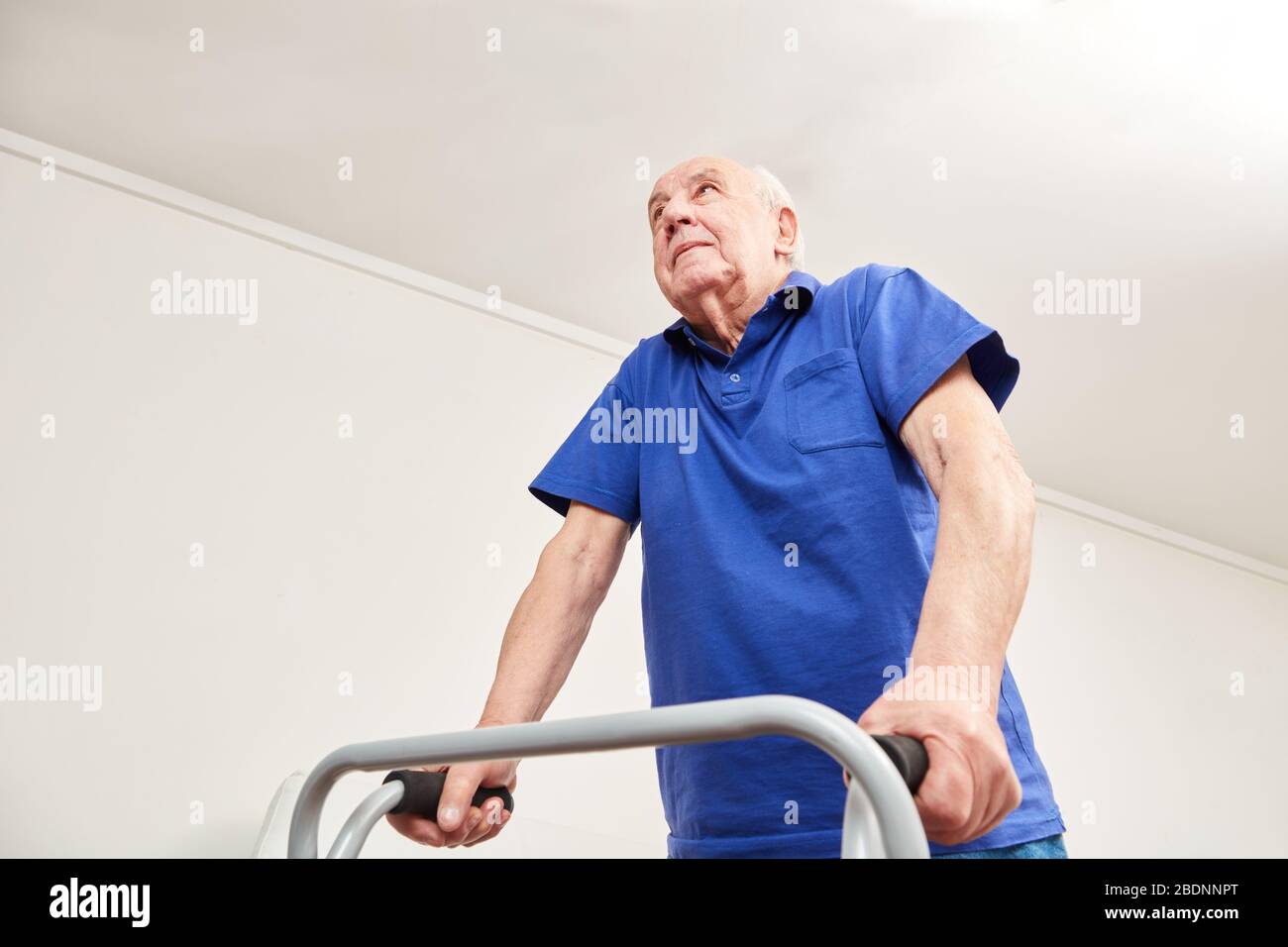 Alter Mann beim gehen mit Gehhilfe in Reha oder Physiotherapie Stockfoto