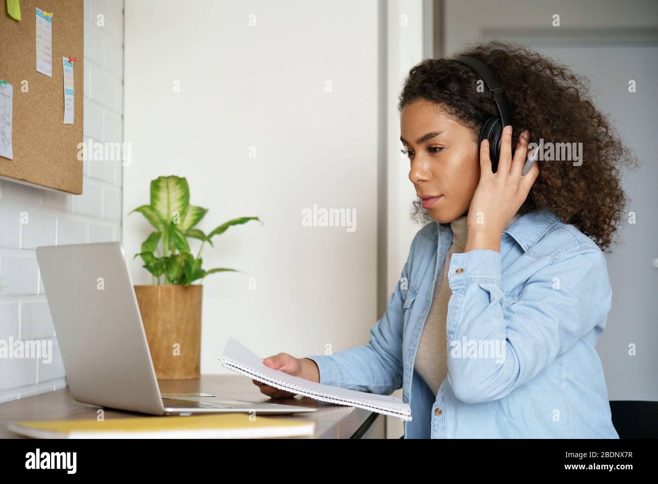 African teen Mädchen Student tragen Kopfhörer Studie online zu Hause auf Laptop. Stockfoto