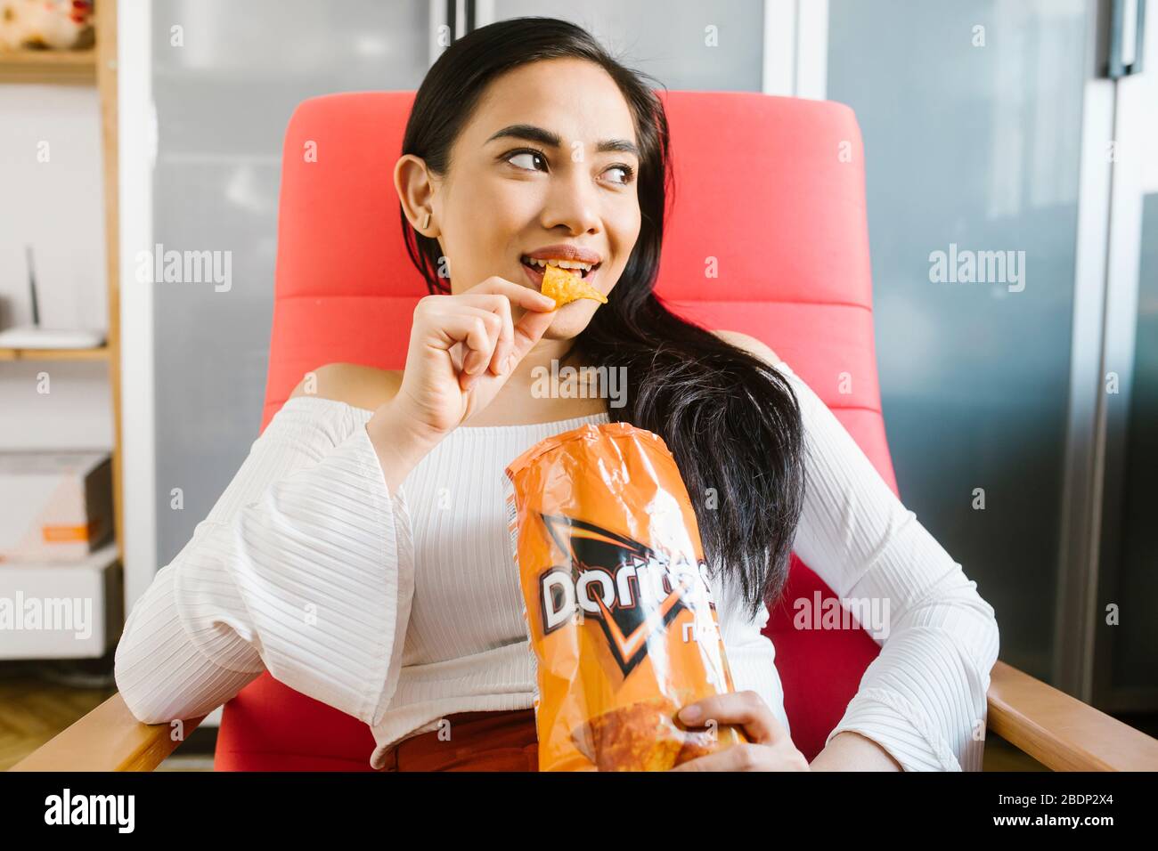 Schöne asiatische Frau essen Doritos. Stockfoto
